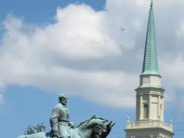 Robert E. Lee Monument, a green-patinated equestrian statue on a stone pedestal with a church steeple and trees behind it.