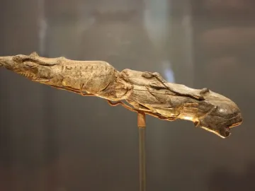 Swimming Reindeer carved from pale tusk material on a metal stand, showing two reindeer figures one behind the other.