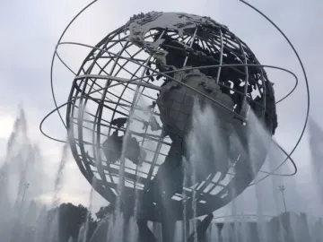 The Unisphere steel globe sculpture with orbital rings, surrounded by water fountains under an overcast sky.