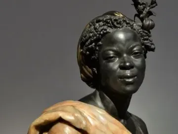 Bust of Woman from the French Colonies with dark textured hair, an ornate hair ornament, and a draped garment over her shoulders.