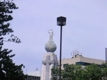 Divino Salvador del Mundo monument with a white statue atop a blue-green globe in a landscaped area