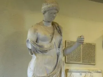 Damaged white marble statue of Armed Aphrodite with a bowed head and one arm missing.