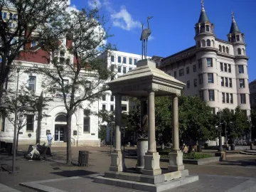 Temperance Fountain in a city square, with a stone pavilion and bird statue above it.