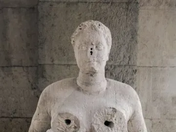 Fontana delle Tette stone sculpture of a female torso with cupped breasts and a simplified face with small perforations.