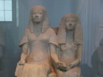 Horemheb and Amenia seated side by side on a stone bench, with their hands joined in the center.