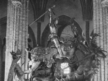 Saint George and the Dragon wooden sculpture showing an armored knight on horseback raising a sword against a dragon, with a crowned figure beside it.