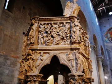 Sant\' Andrea Pulpit with densely carved figures, a large eagle, and Gothic arches inside a church interior.