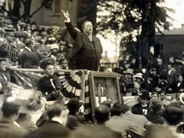 William Howard Taft speaks from a raised platform at the unveiling of the George Armstrong Custer Equestrian Monument, with crowd and bunting below.