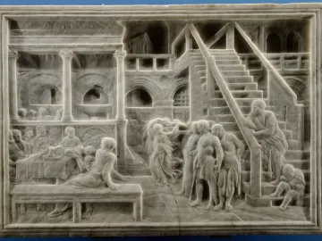 The Feast of Herod marble relief with figures gathered around a banquet table, a dancing woman in the center, and arched colonnades behind them.