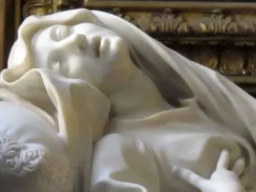 Detail of Ecstasy of Blessed Ludovica Albertoni, showing the marble figure reclined with eyes closed and a hand resting on the chest.