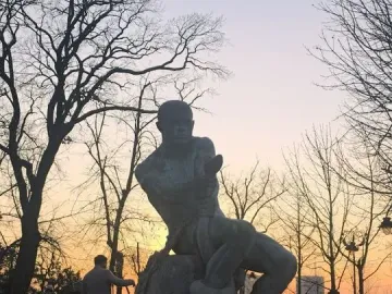 Fisherman Fountain bronze statue of a man wrestling a serpent on a dark fountain base at dusk.