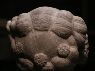 The back of Verrocchio\'s Bust of a Young Woman, showing an intricately carved hairstyle with waves, bands, and floral rosettes.