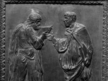 Door of the Apostles bronze relief showing two haloed, robed men facing each other as one hands an object to the other.