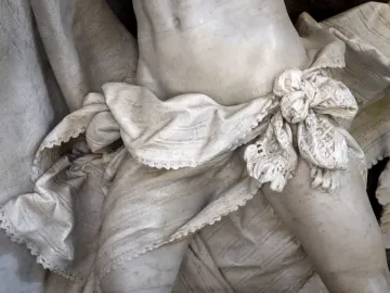Close-up of the Angelo Nocchiero sculpture showing marble drapery tied at the waist over the figure\'s midsection.