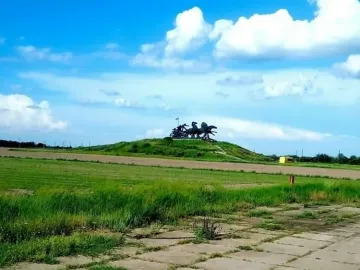 Legendary Tachanka monument on a grassy hill under a blue sky with clouds