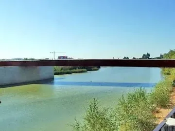 Aerial view of the Puente de Miraflores spanning a wide greenish river