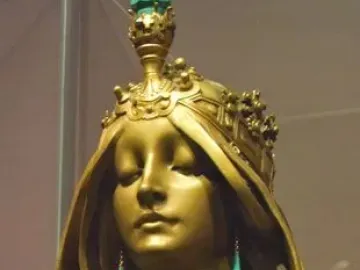 Polished bronze bust of a woman with closed eyes, wearing an ornate crown and long teal earrings.