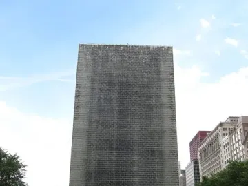 Crown Fountain in Chicago with water cascading down a tall tower as people gather around the reflective pool.