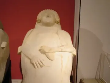 Lady of Cádiz stone sculpture of a woman with curly hair and hands resting over her midsection.