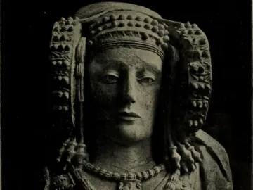 Stone bust of the Lady of Elche with an ornate headdress and layered necklaces.
