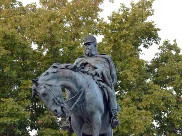Monument to General Martínez-Campos, a weathered bronze equestrian statue against leafy trees.