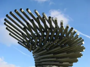 The Singing Ringing Tree sculpture made of grey metal pipes against a blue sky.