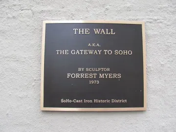 A dark metallic plaque for The Wall mounted on a light textured wall.