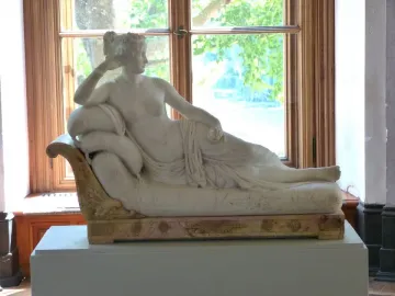Venus Victrix, a reclining white marble statue of a partially nude woman on an ornate daybed, holding a small round object.