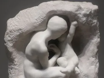 Young Mother in the Grotto, a white marble sculpture of a crouching mother embracing a child within a rough grotto-like form.