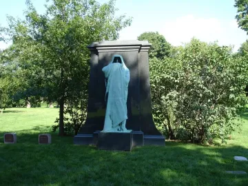 Eternal Silence sculpture with a hooded, green-patinated figure standing before a tall stone monument.