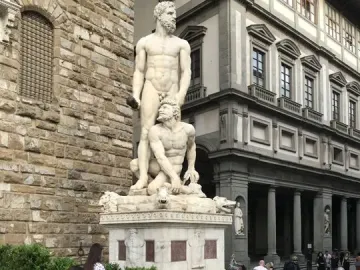 Hercules and Cacus sculpture on an ornate pedestal in Piazza della Signoria, showing two muscular figures in white marble.