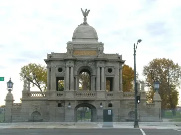 Hurlbut Memorial Gate with a stone arched entrance, cupola, and eagle statue on top.