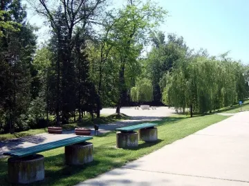 Table of Silence surrounded by hourglass-shaped chairs in a park setting.