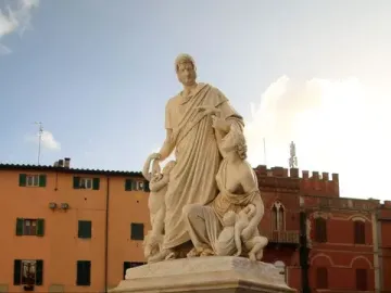Canapone monument with a central standing male figure, seated female figure, and children on a tall stone pedestal in a town square.