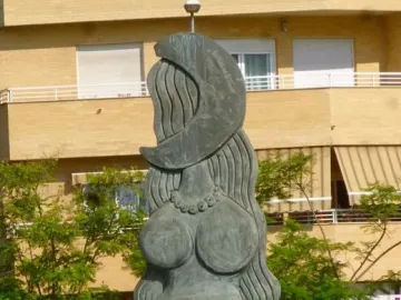 Dona Lluna bronze sculpture with a female torso, long wavy hair-like forms, and a crescent moon on top.