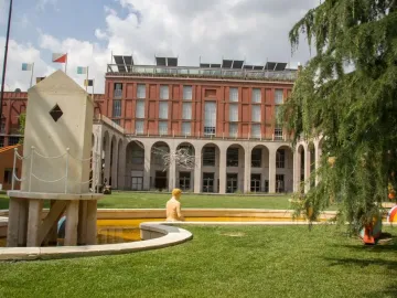 The Mystery Baths fountain with a golden bather statue beside a small angular tower-like structure in a park.