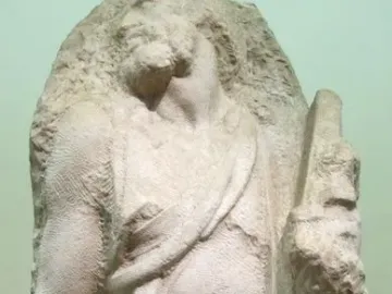 Saint Matthew sculpture carved from a rough stone block, with the figure emerging in a strained pose.
