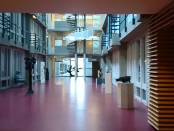 Homunculus Loxodontus sits along a hallway beside large windows.