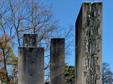 Julius Fučík Memorial with three tall stone steles in a snowy park, one carved with relief figures and abstract shapes.