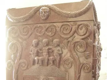 Sarcophagus of Constantina with relief carvings of figures stomping grapes in a vat, framed by grapevines and a garland above.