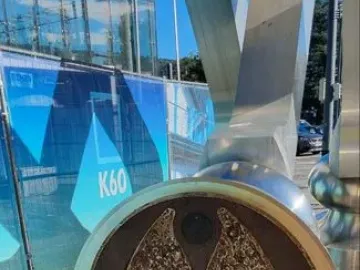 Close-up of the S-Printing Horse base with a textured bronze-colored circular metal plate and an embedded light on the paved ground.
