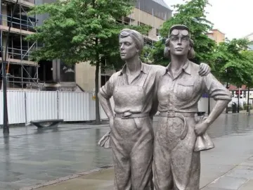 Women of Steel sculpture in Sheffield, showing two metal figures in work clothes on a dark base outdoors.