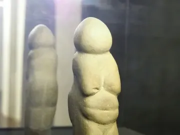 Venus of Chiozza figurine displayed on a dark circular base inside a case.