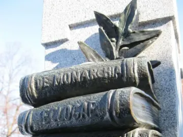 Book-shaped reliefs on La mort de Dante, including embossed titles and sculpted leaves above a granite surface.