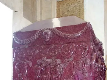 Sarcophagus of Constantina with carved grape-harvesting figures and vines on a red porphyry surface.