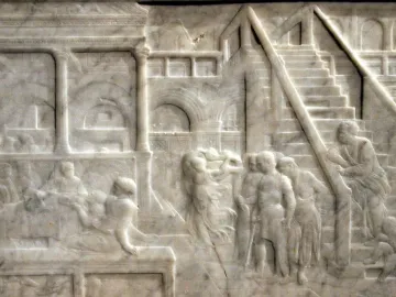 The Feast of Herod stone relief showing banquet figures beneath arches and stairs in a detailed architectural setting.