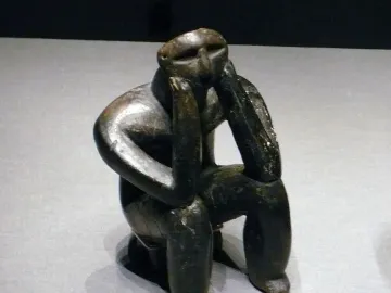 The Thinker of Cernavodă figurine seated with its head resting on its hands.