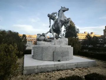 The Torch Bearers sculpture shows a rearing horse and two figures on a circular pedestal in a landscaped outdoor setting.