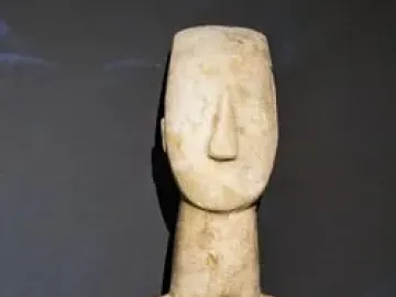 Cycladic marble female figurine with folded arms and a long neck.