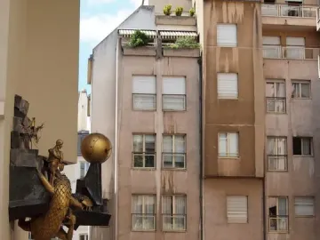 The Defender of Time sculpture shows a golden figure battling a scaly creature with a golden orb mounted on a building in Paris.